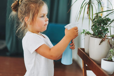 Girl holding plant at home