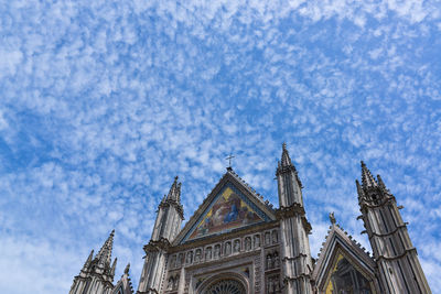 Low angle view of duomo di orvieto against cloudy blue sky