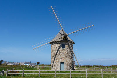 Traditional windmill on field against clear blue sky