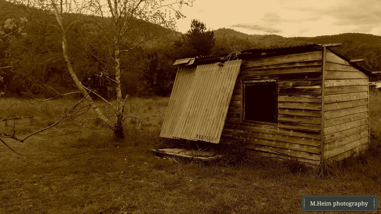 built structure, architecture, building exterior, house, sky, tree, text, outdoors, no people, day, nature, tranquility, residential structure, mountain, plant, western script, tranquil scene, abandoned, cloud - sky, bare tree