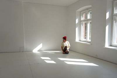 Full length of man woman looking away while sitting on floor at home