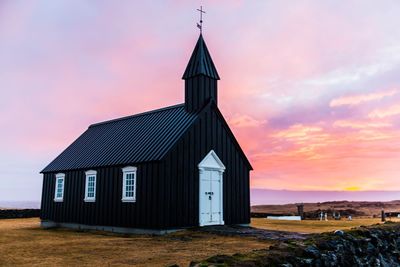 Exterior of house on field against sky during sunset