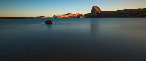 View of calm blue sea against mountain range