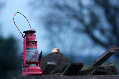 Close-up of red bottle on metal structure against sky