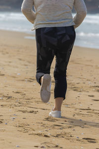 Low section of man walking on beach