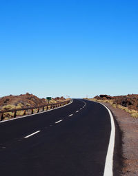 Road by mountain against clear blue sky