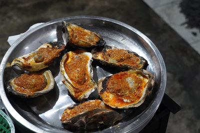 Grilled oyster at jakarta food streets vendor. sizzling on a grill,