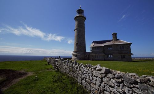 Lighthouse by sea against sky