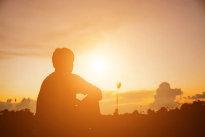 Silhouette man standing against orange sky