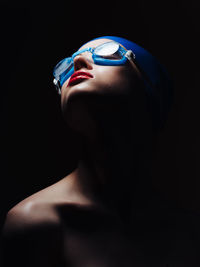 Close-up portrait of mid adult woman against black background