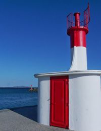 Red lighthouse against clear blue sky