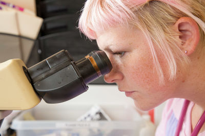 Close-up of woman looking through telescope