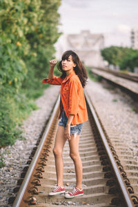 Full length portrait of woman standing on railroad tracks