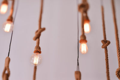 Low angle view of illuminated light bulbs hanging on ropes
