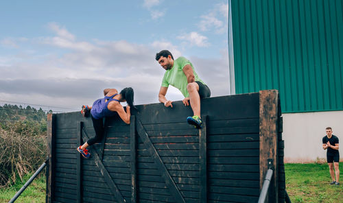 People climbing on wooden wall outdoors