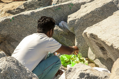 Rear view of man sitting on rock