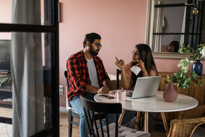 Young woman using mobile phone while sitting at home