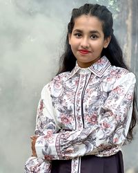 Portrait of young woman standing against smoke 