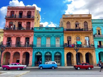 Cars on road by colorful building in city