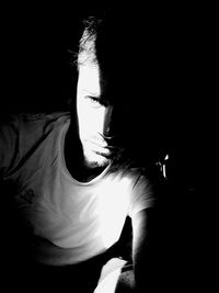 Portrait of young man sitting in darkroom