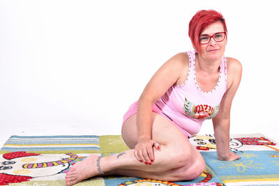 Portrait of woman sitting against white background