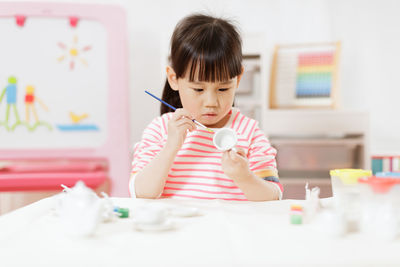 Young girl decorating hand made craft for homeschooling