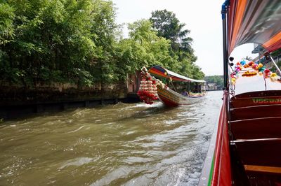 Boat sailing on river by trees