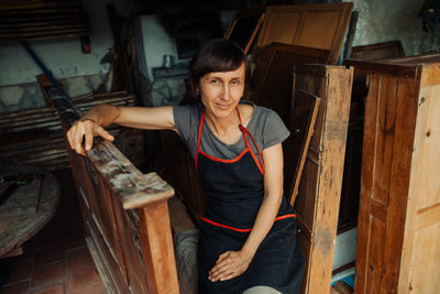Female carpenter resting in workshop looking at camera