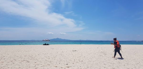 Rear view of man standing on beach against sky