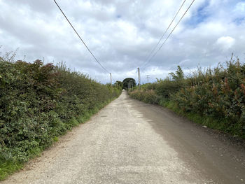 Looking along, thornham lane, with high hedges, and a cloudy sky in, rochdale, lancashire, uk