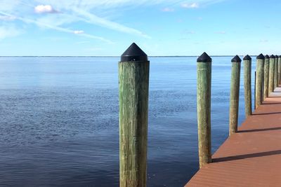 Wooden posts on sea against sky