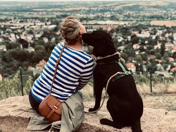 Rear view of woman with dog sitting on rock