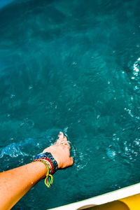 Cropped hand of young woman touching water