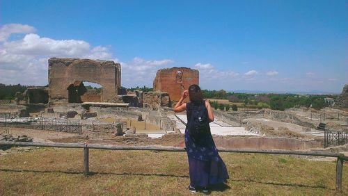 Woman standing in front of old ruin against sky