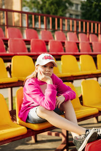 A sad girl in a white cap is sitting on the school bleachers after lessons
