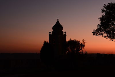 Silhouette built structure against sky at sunset