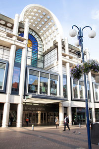 People walking on street against modern buildings in city