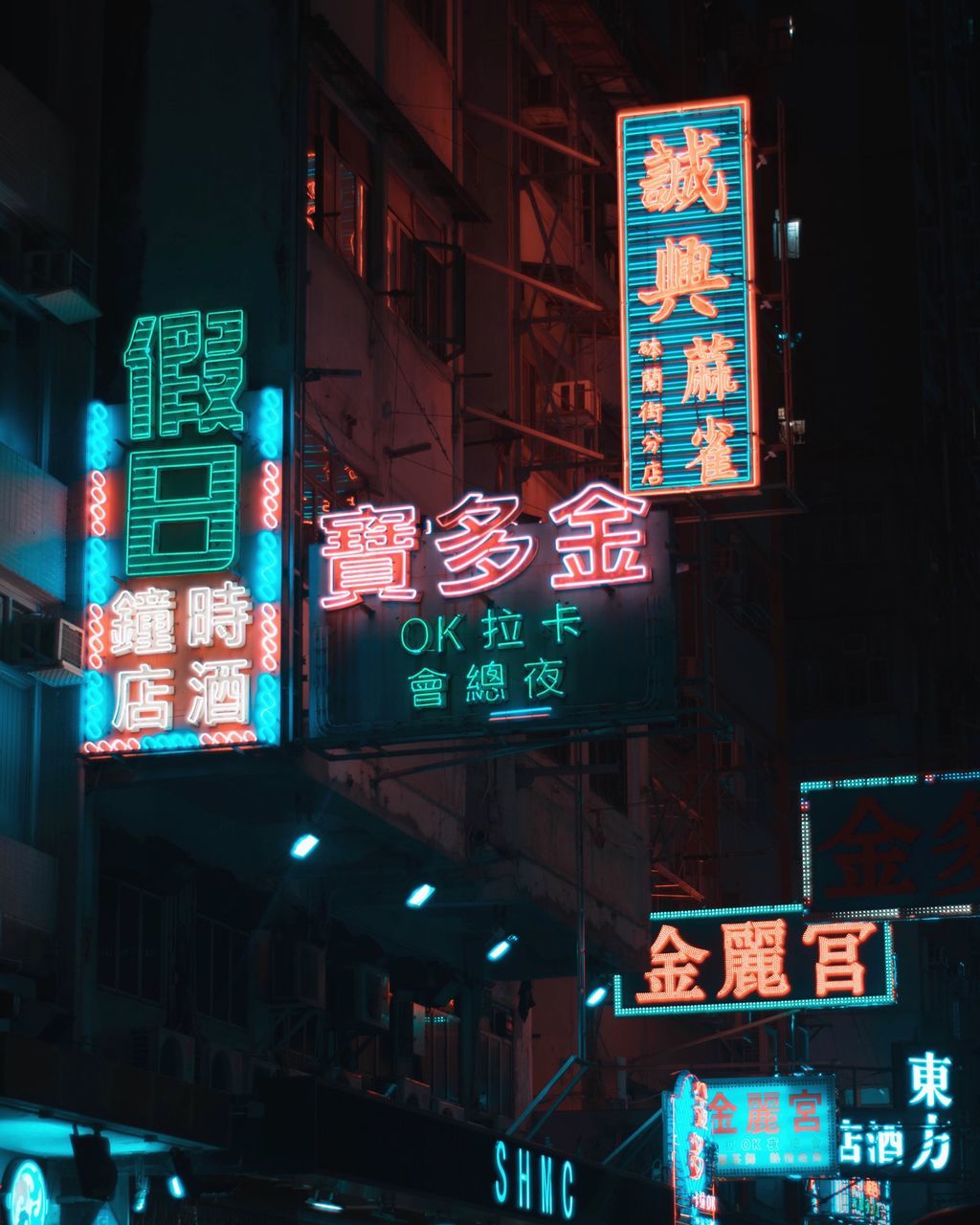 LOW ANGLE VIEW OF ILLUMINATED INFORMATION SIGN ON STREET AGAINST BUILDINGS