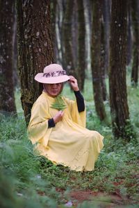 Side view of young woman standing in forest