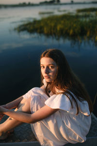 Portrait of young woman sitting on lake