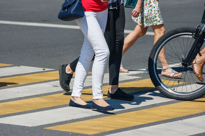 Low section women walking on zebra crossing in city