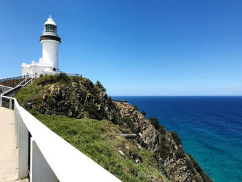 Lighthouse amidst sea and buildings against sky