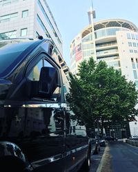 Cars on street by buildings in city against sky