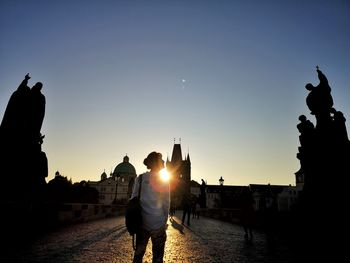 Rear view of silhouette people walking on water at sunset