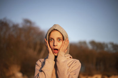 Portrait of girl with surprised expression against sky