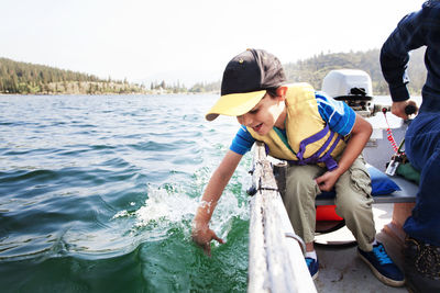 Happy son playing in water while traveling with father in motorboat on lake