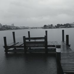 Empty bench on pier by sea against sky