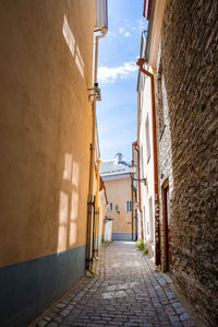 Empty cobbled alley amidst residential buildings in old town at city against sky