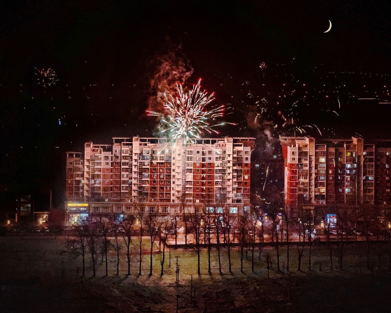 FIREWORK DISPLAY IN ILLUMINATED CITY AT NIGHT