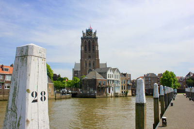 Buildings at waterfront against cloudy sky